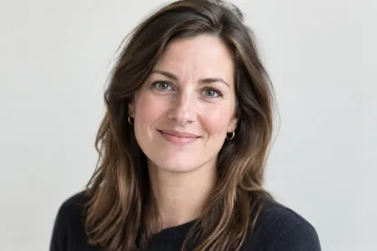 Portret van een vrouw met schouderlang bruin haar in een lichte blouse, vriendelijk lachend